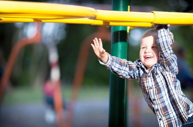 Kid climb with beautiful smile on monkey bar